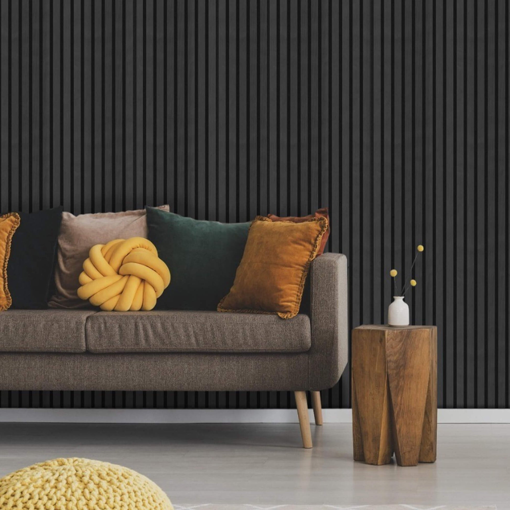 Gray sofa with colorful cushions against a black paneled wall.