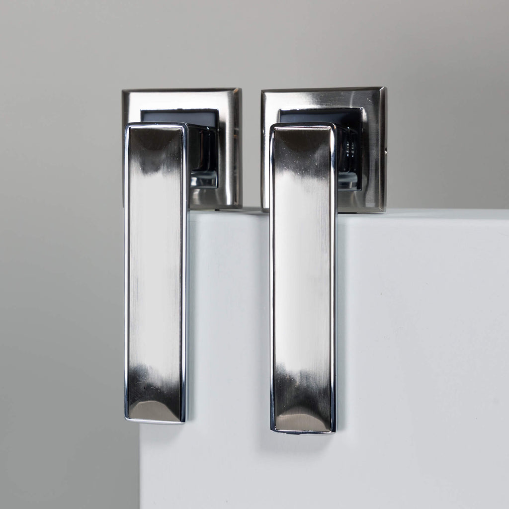 A pair of Alto Matt Satin Black & Polished Chrome Square Rose Handles on a grey background