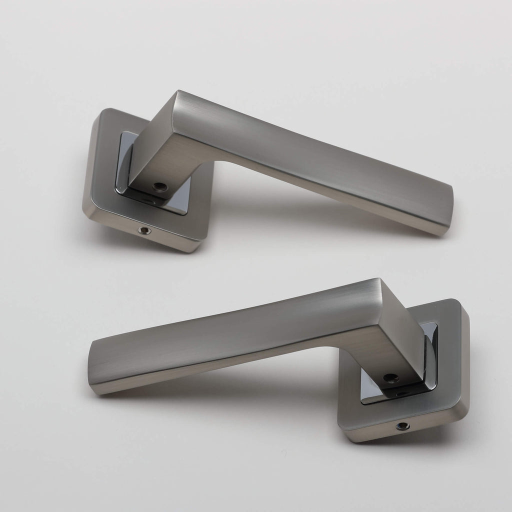 A pair of Artemis Matt Satin Nickel & Polished Chrome Square Rose door handles on a light grey background.