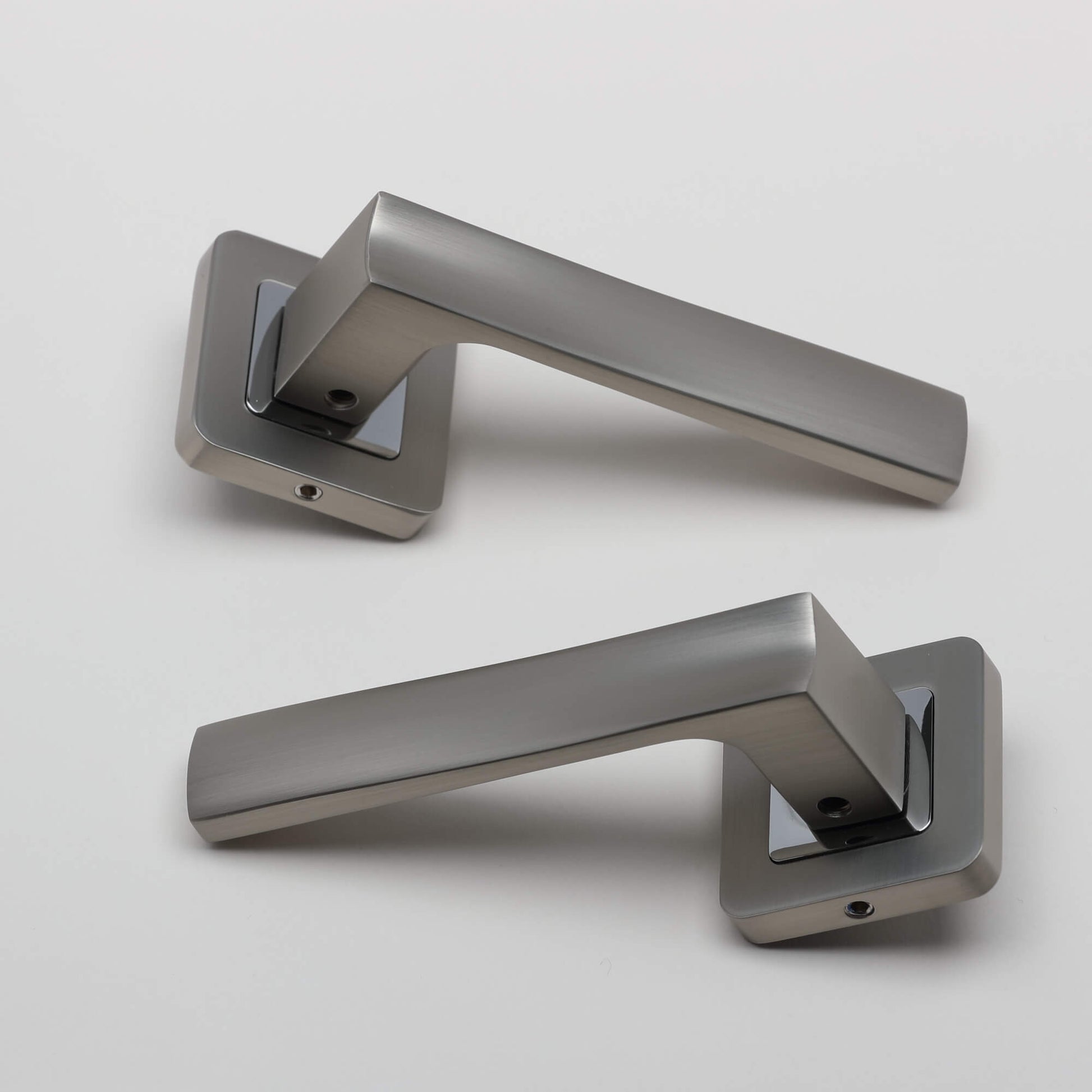 A pair of Artemis Matt Satin Nickel & Polished Chrome Square Rose door handles on a light grey background.