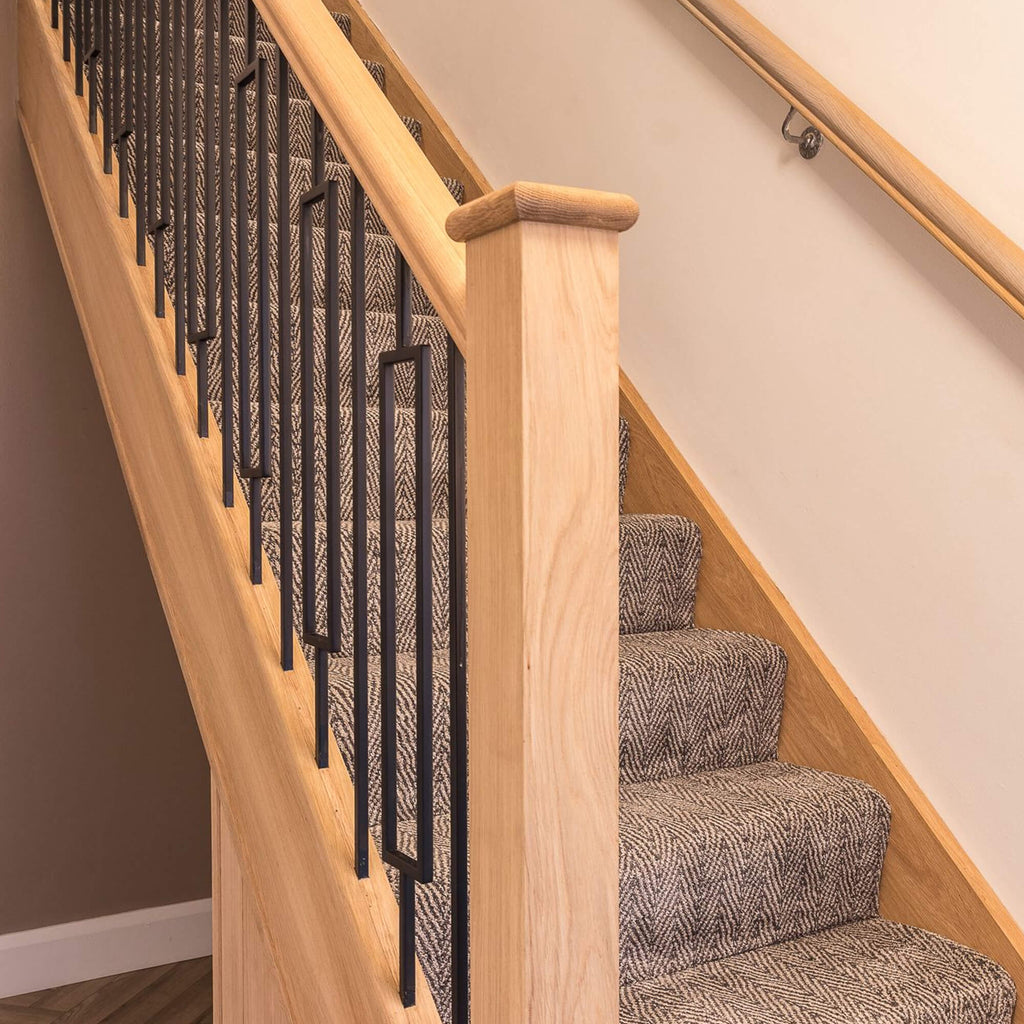 Staircase with wooden handrail and black rectangle spindles in a home interior setting.
