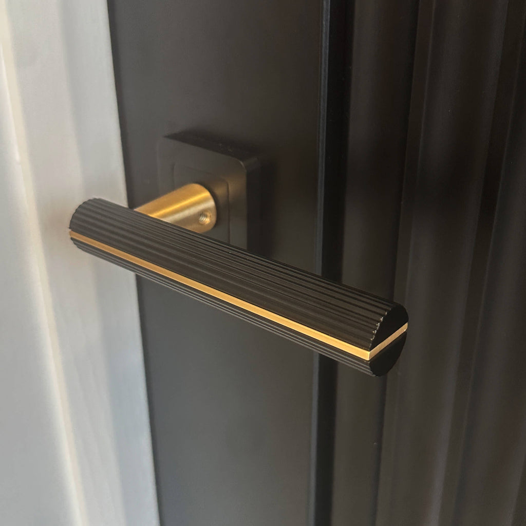 Close-up of a Calvus Flat Black & Satin Brass Square Rose Handle on a Black Reeded Internal Door.