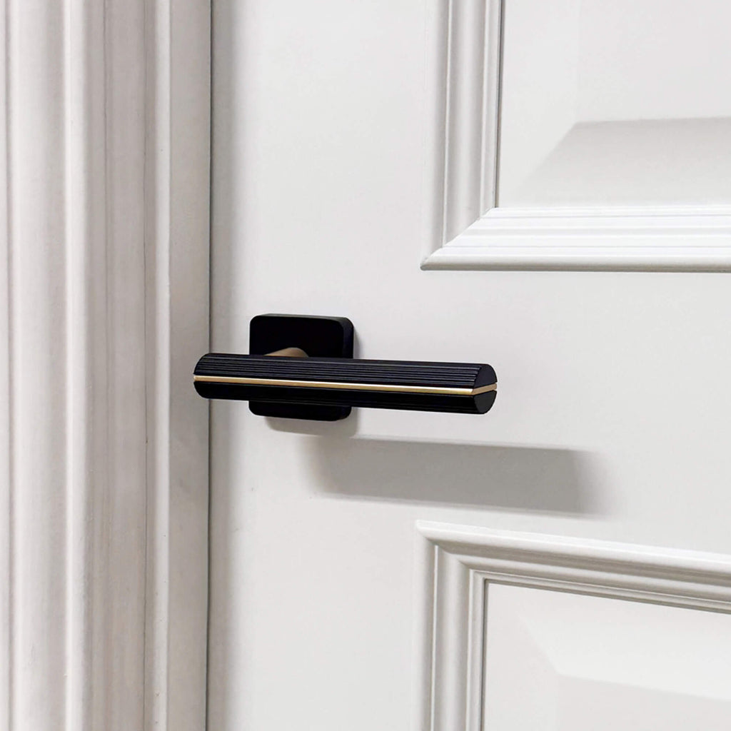 A Calvus Flat Black & Satin Brass Square Rose Handle on a white internal door