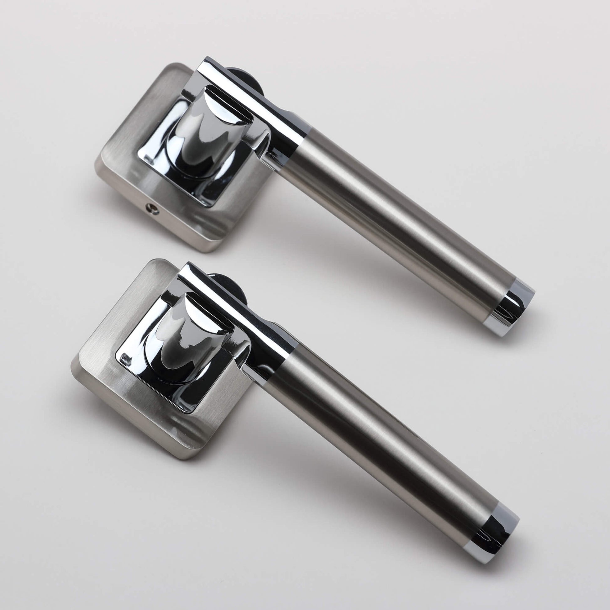 An angled view of a pair of Cumulus Nickel Brushed & Polished Chrome Square Rose Handles on a light grey background.