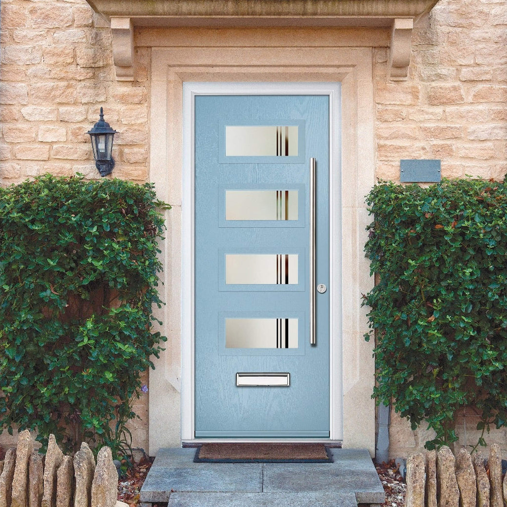 A Light blue Grasmere Composite GRP External Door with four rectangles glass panes with a metallic mail slot and handle on a stone building facade.
