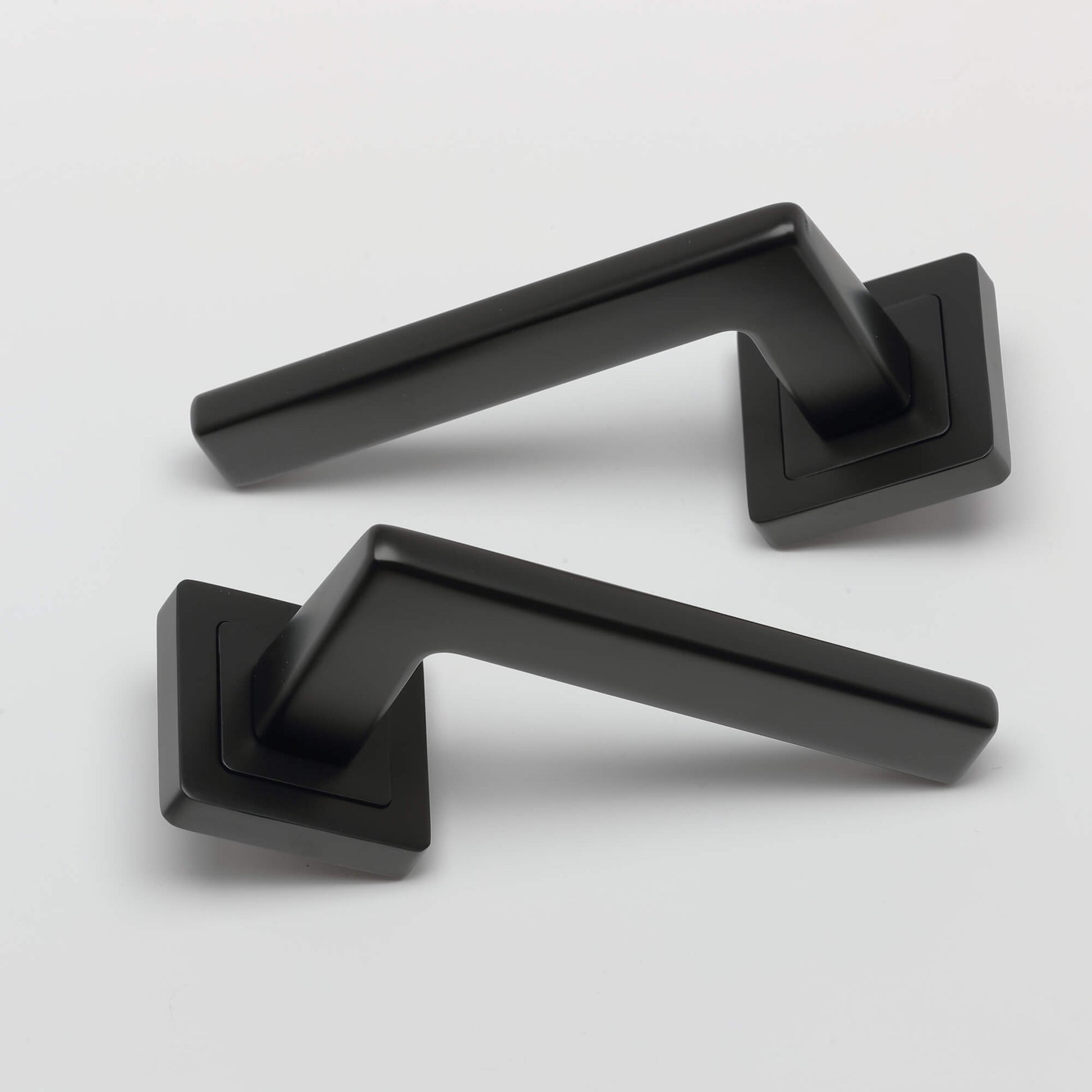 A pair of Hera Flat Black Square Rose door handles on a light grey background.