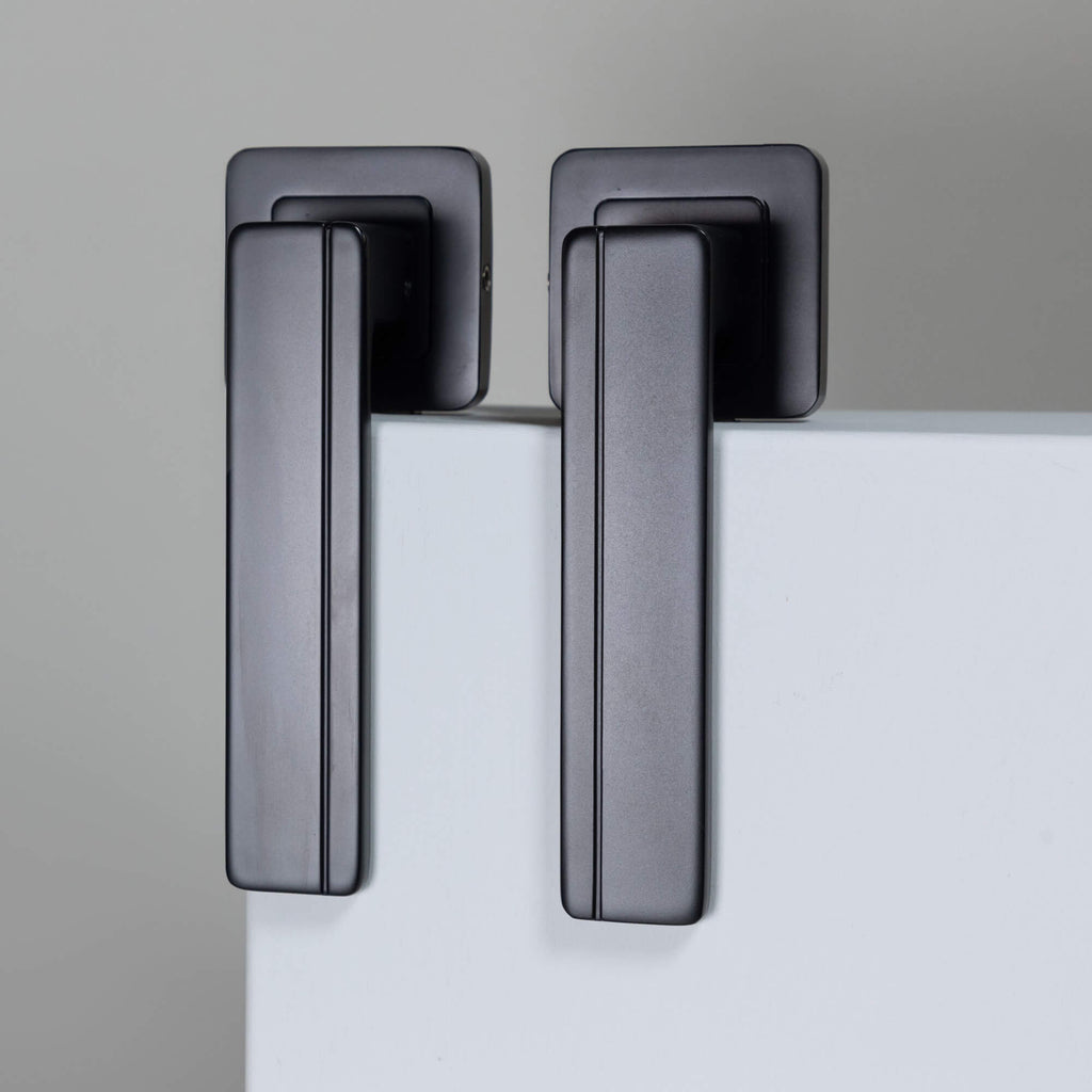 A Hermes Flat Black Square Rose door handle on a white door with a grey background