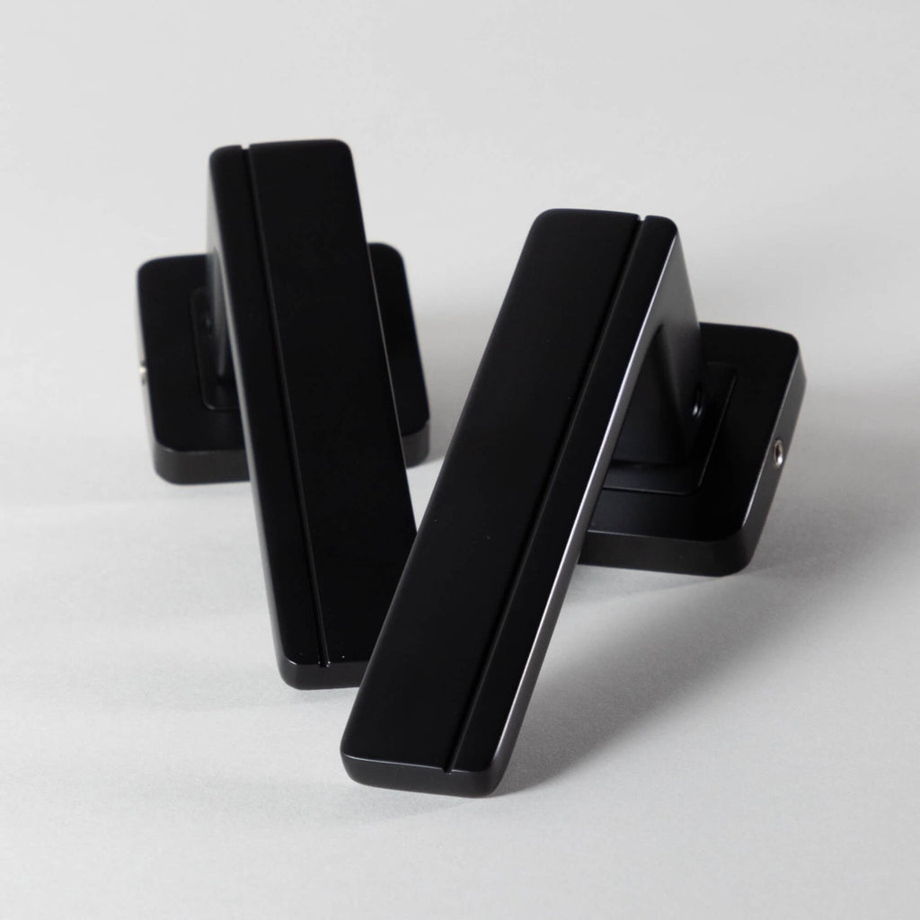 A set of Hermes Flat Black Square Rose door handles on a light grey background
