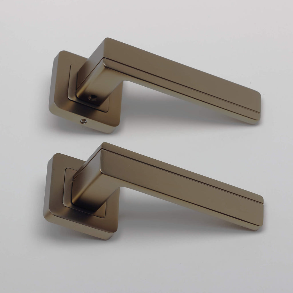 A side view of a pair of Hermes Matt Coffee Square Rose Handles on a grey background.
