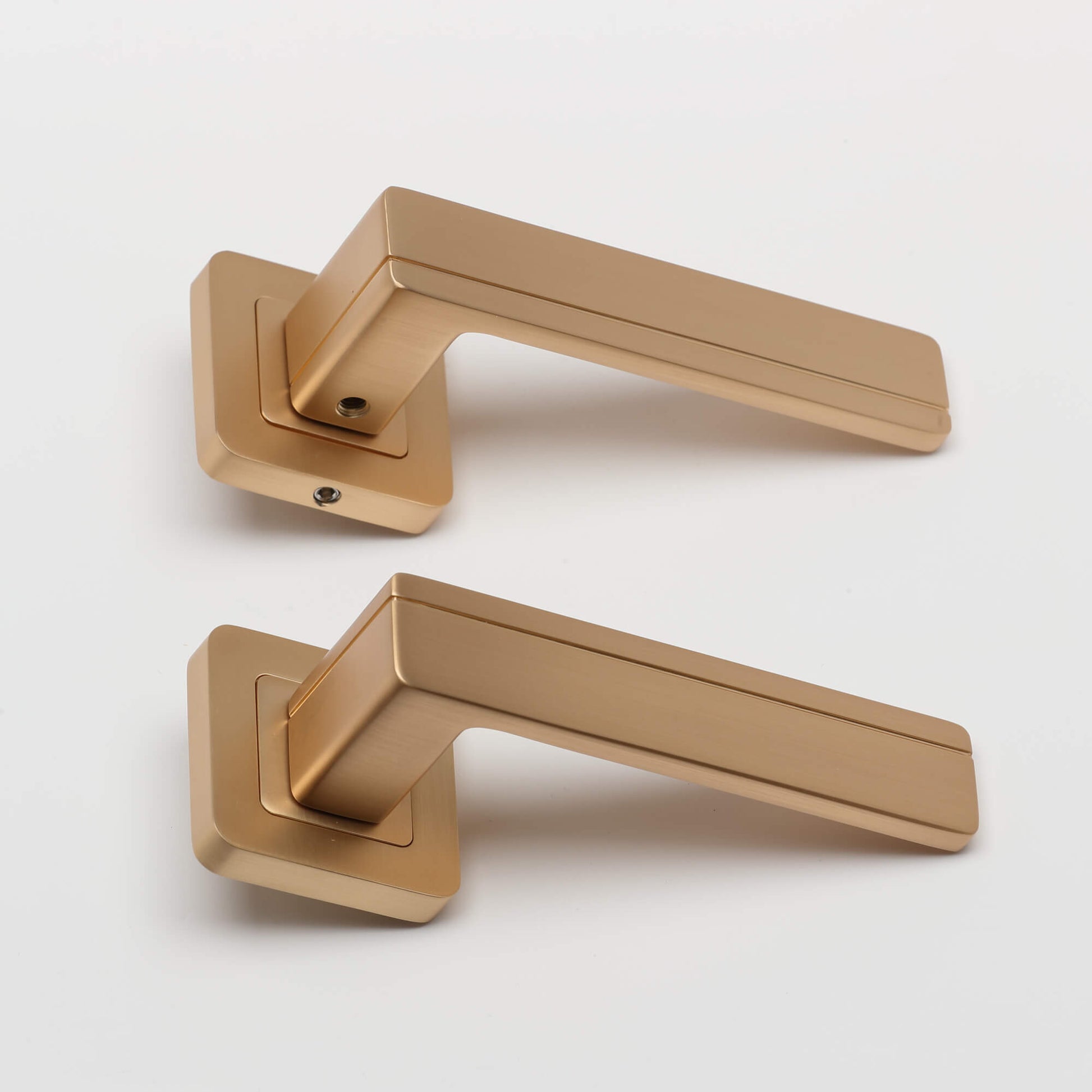 Pair of Hermes Satin Brass Square Rose door handles on a white background.