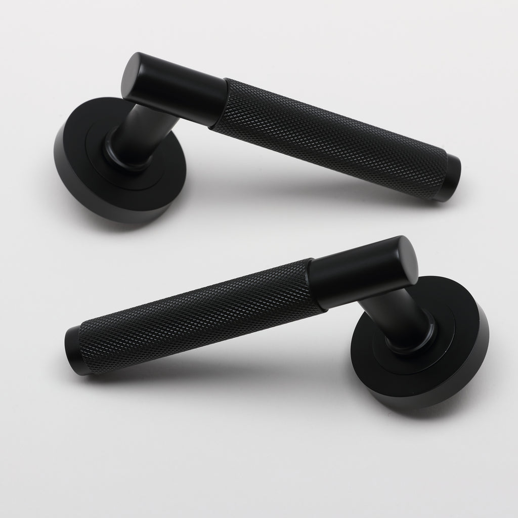 A pair of Knurled Flat Black door handles on a grey background.