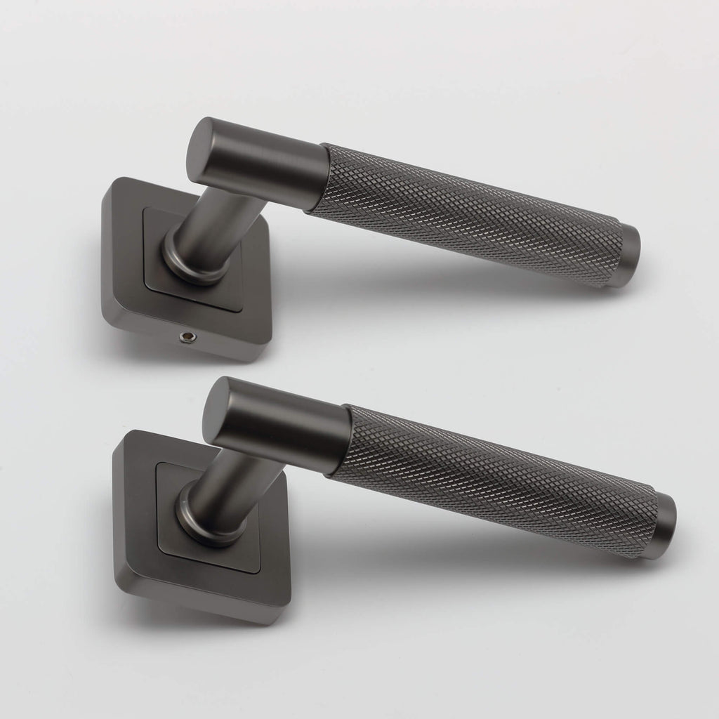 A side view of a pair of Knurled Matt Satin Black Square Rose Door Handles on a grey background.