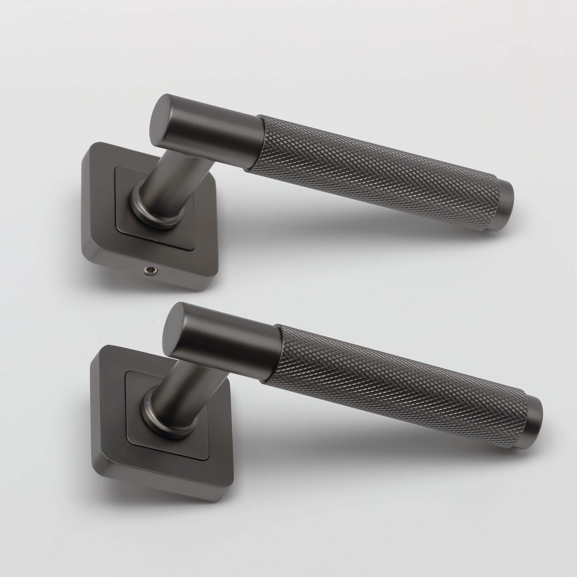 A side view of a pair of Knurled Matt Satin Black Square Rose Door Handles on a grey background.