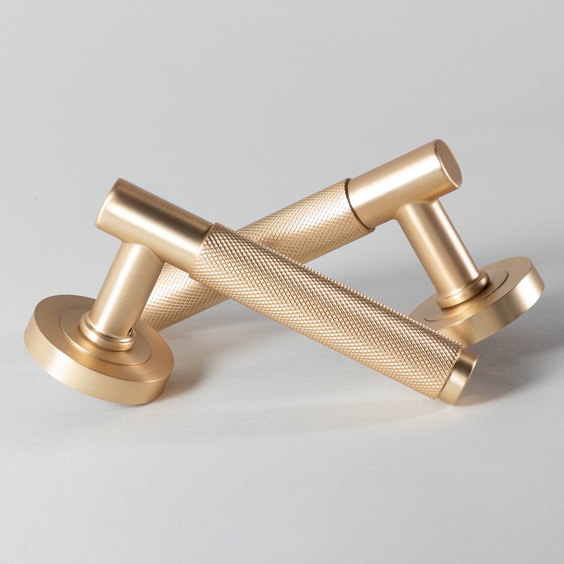 A Knurled Satin Brass Handle door handle set on a light gray background