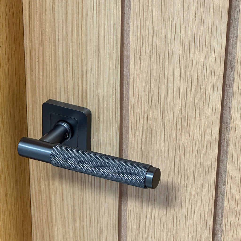 Close-up of the grooves and woodgrain of a Mexicano White Oak 40mm Internal Door, with a Matt Satin Black Knurled Handle.