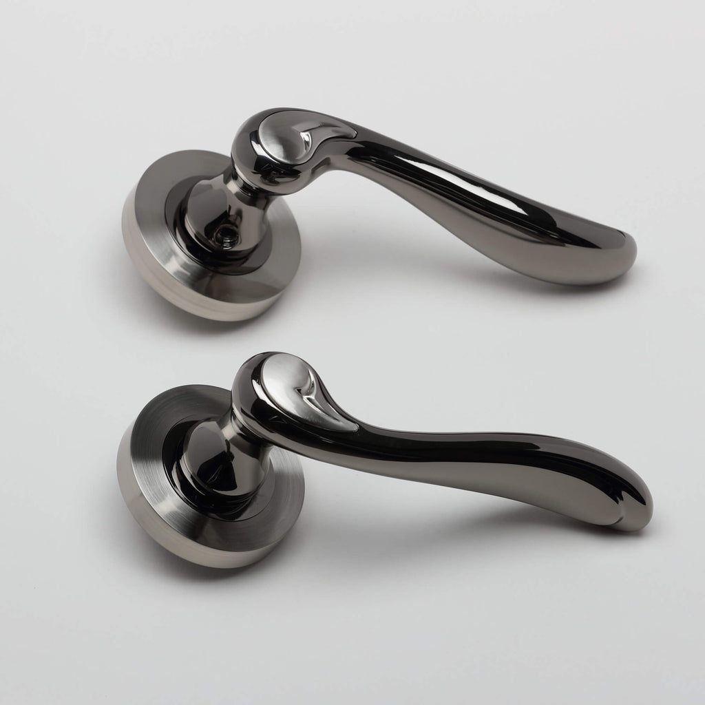 A side view of a pair of Monet Black Nickel & Nickel Brushed Round Rose Door Handle on a white background.