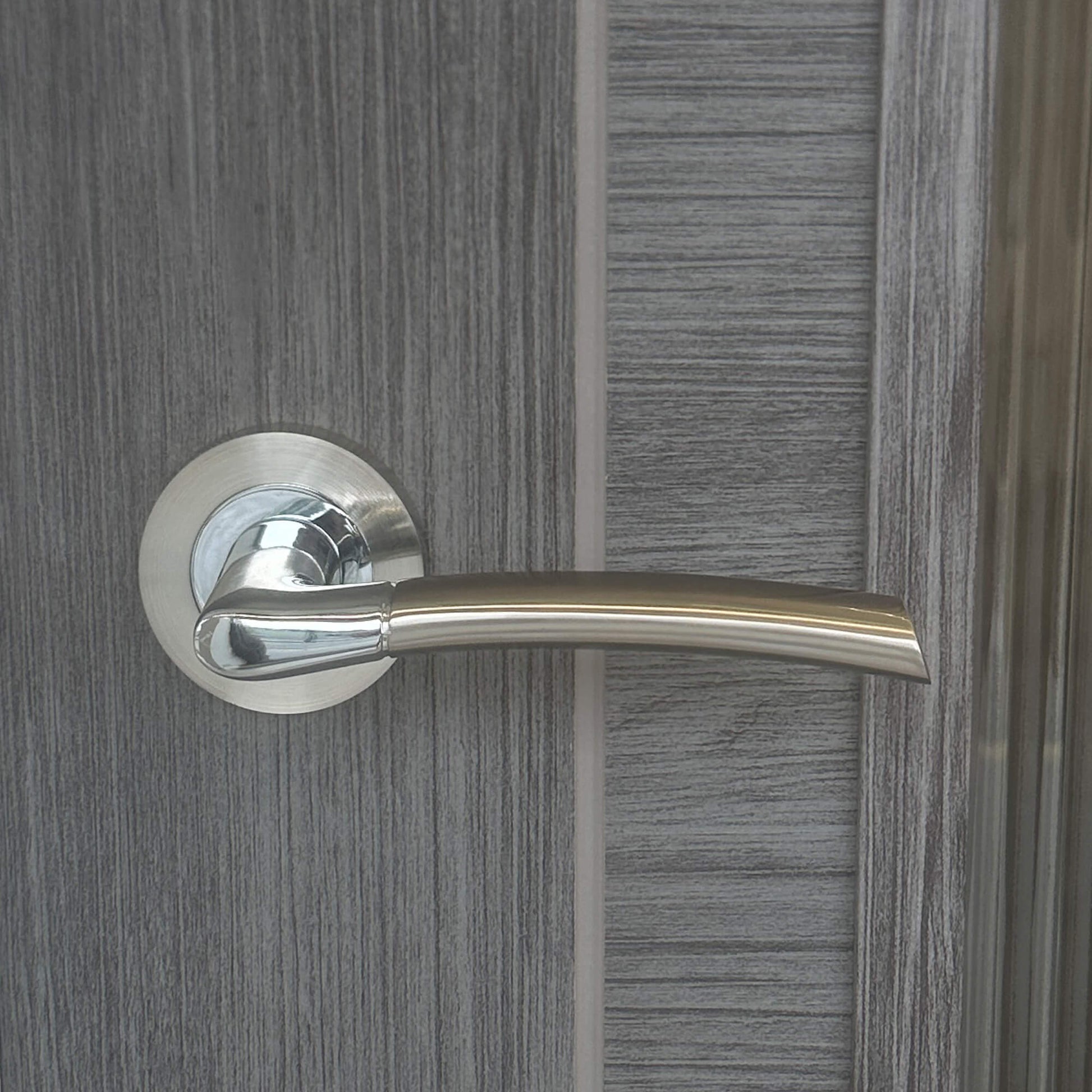 Close-up of a Storm Nickel Brushed & Polished Chrome Handle on a wooden door