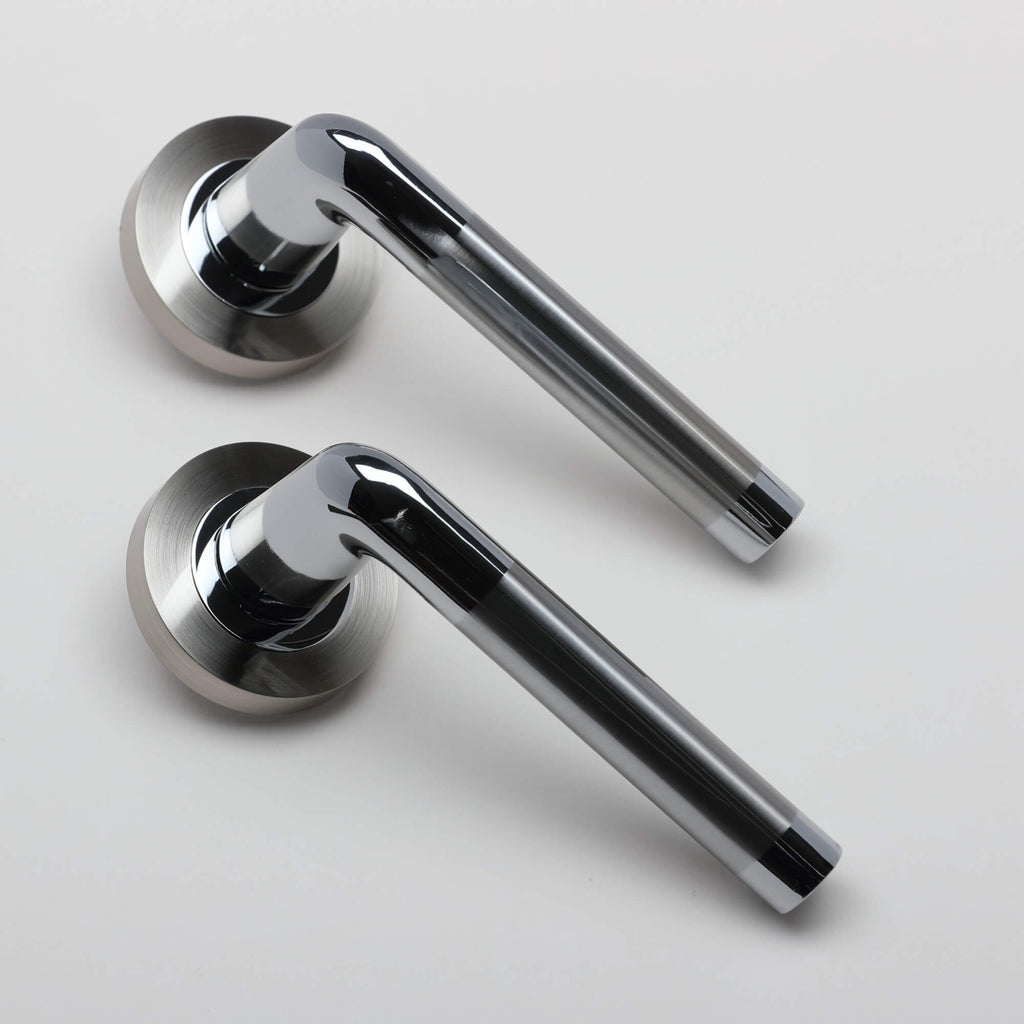 An angled view of a pair of Tempest Nickel Brushed & Polished Chrome door handles on a grey background.