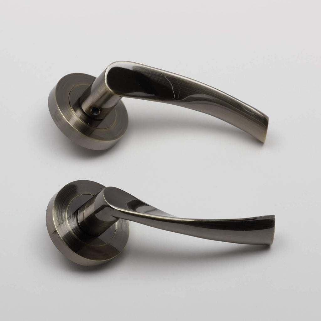 Side view of a pair of Trade Range Antique Brass door handles on a grey background.