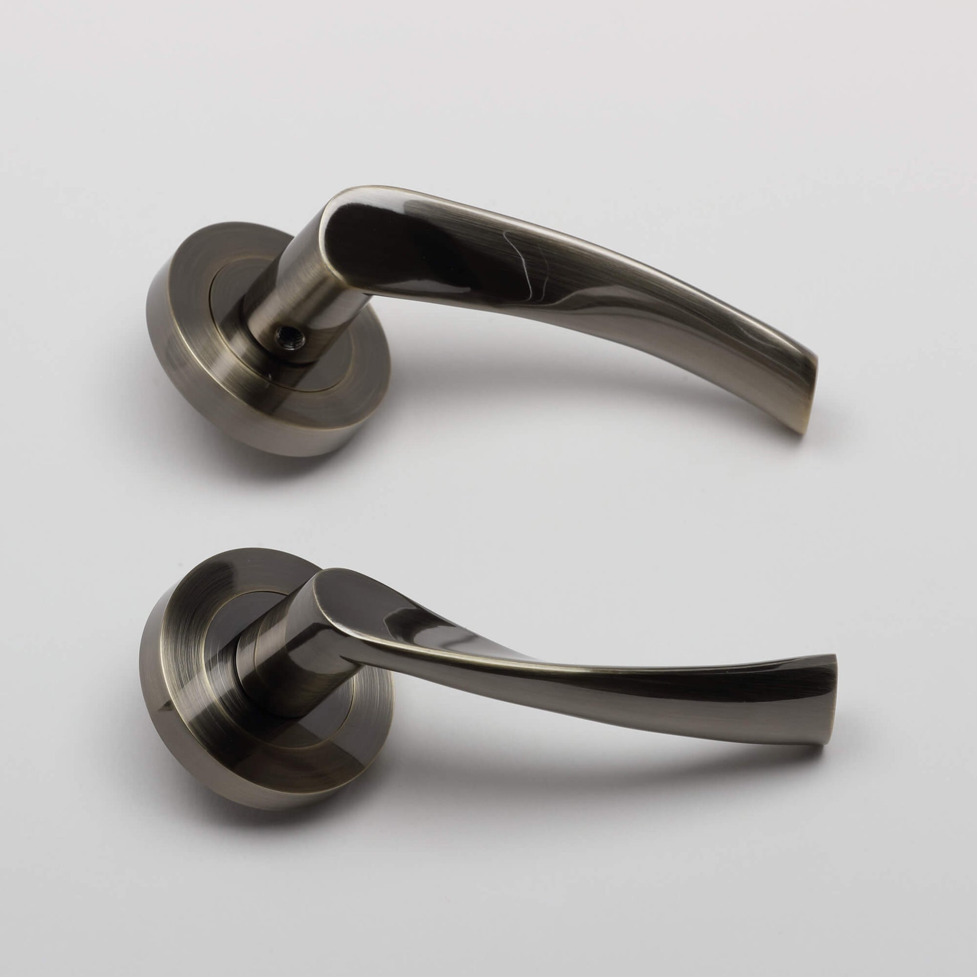 Side view of a pair of Trade Range Antique Brass door handles on a grey background.