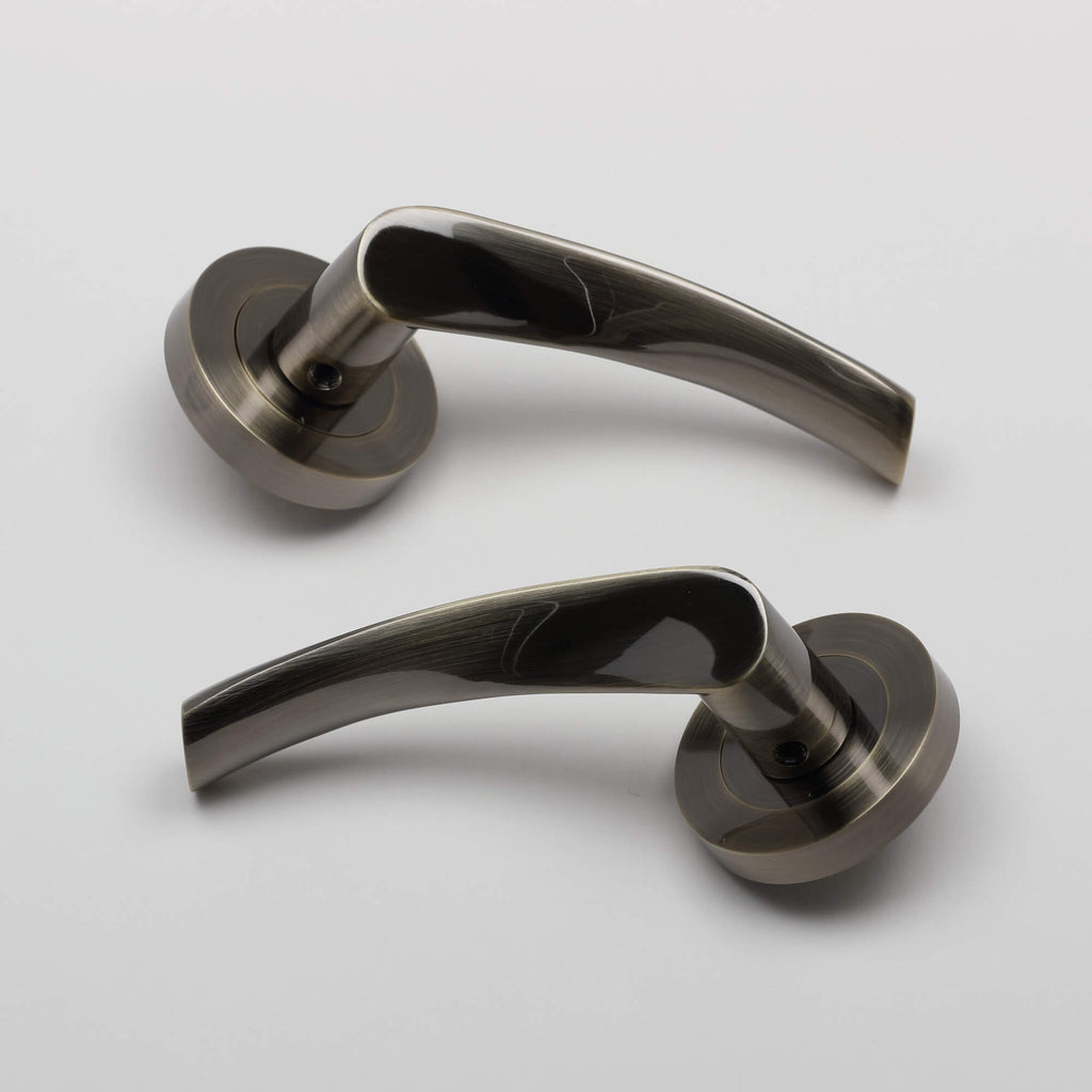 A pair of Trade Range Antique Brass door handles on a grey background.