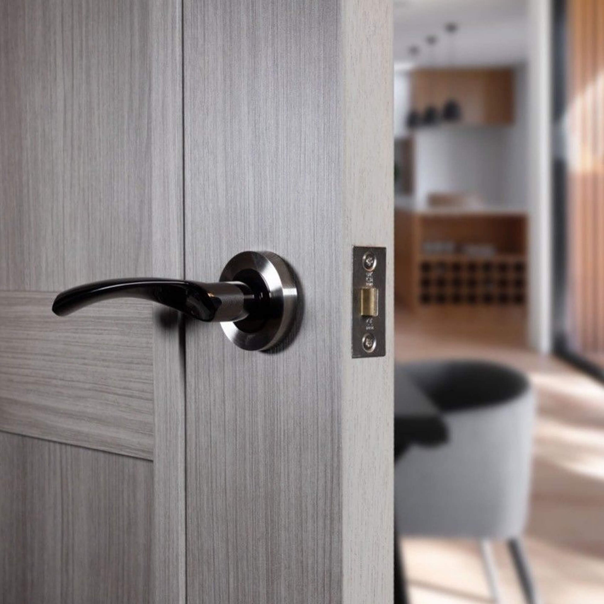 Close-up of a gray door with a Trade Range Black Nickel & Nickel Brushed Handle, in an interior setting.