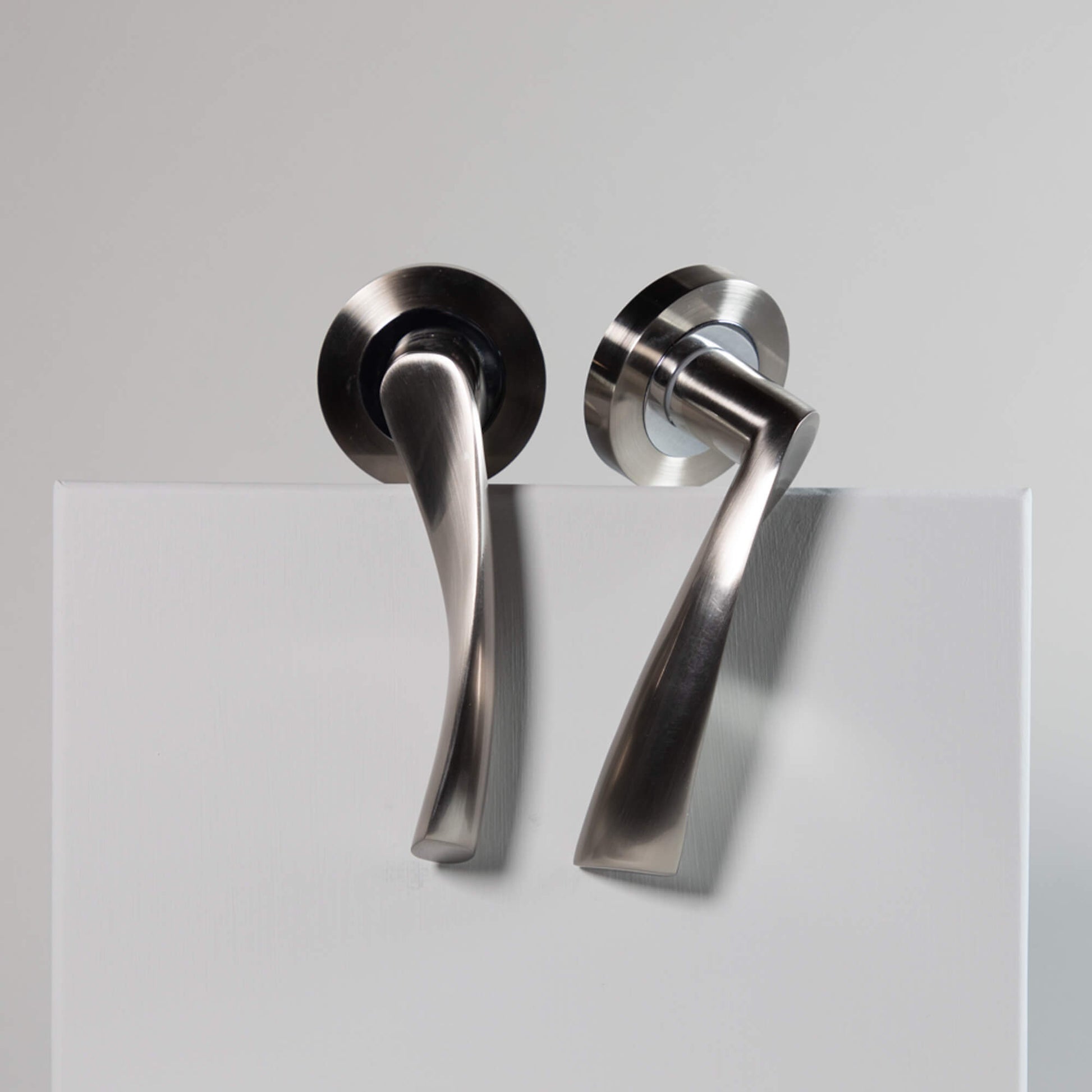 A set of Trade Range Nickel Brushed & Polished Chrome door handles on a grey background