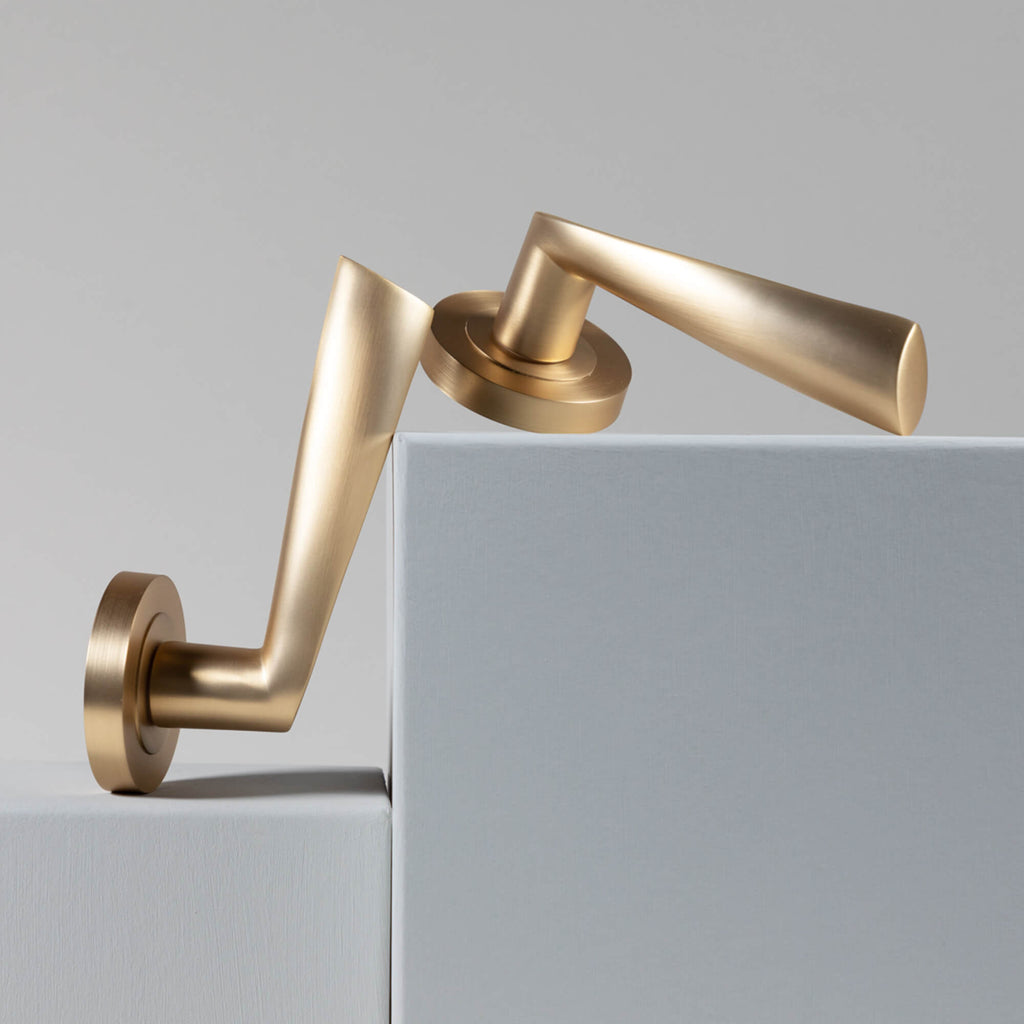 A Trade Range Satin Brass door handle set on a grey background.
