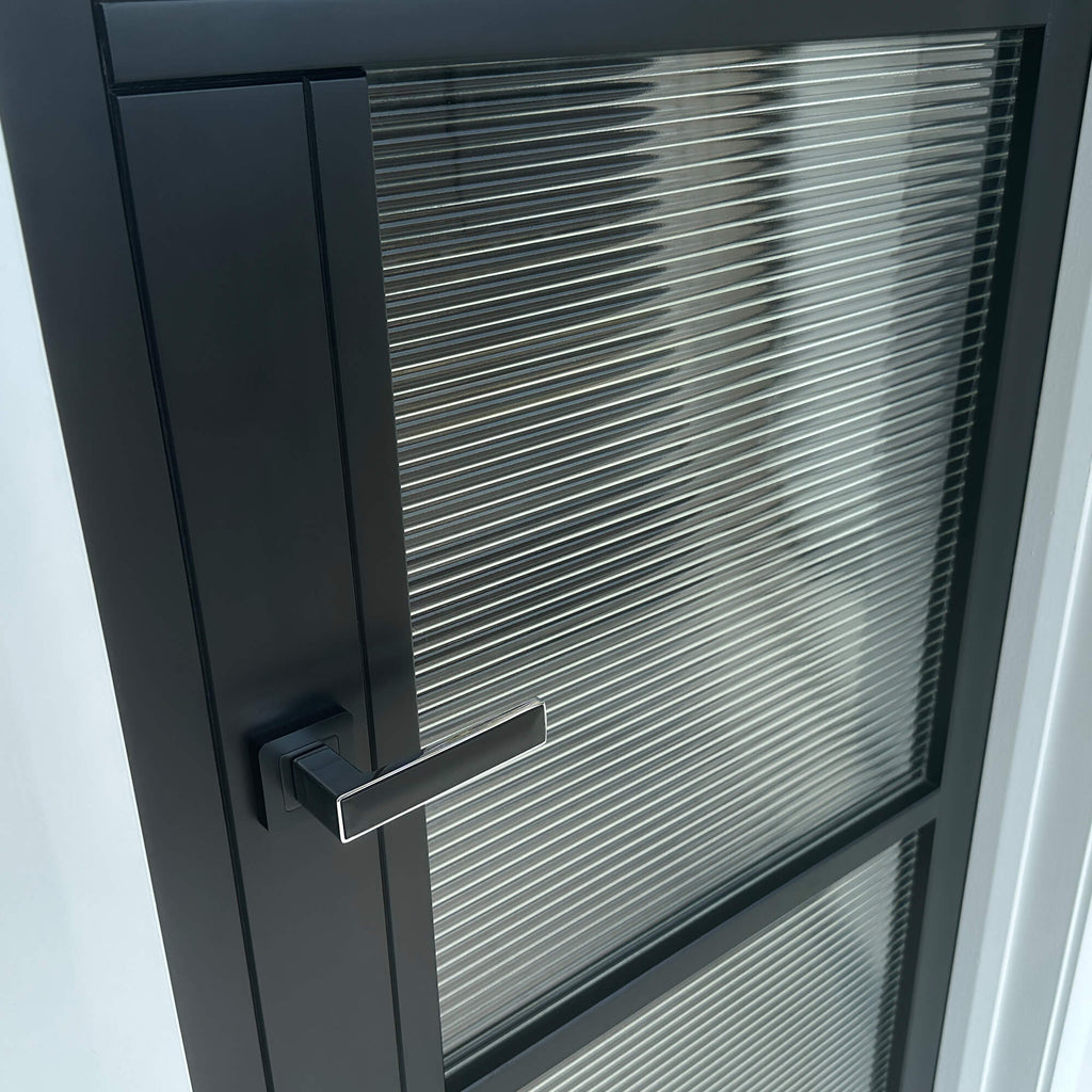 Close-up of a Tribeca Black Primer Plus 3 Lite Reeded 40mm Internal Glass Door with an Alto handle. 