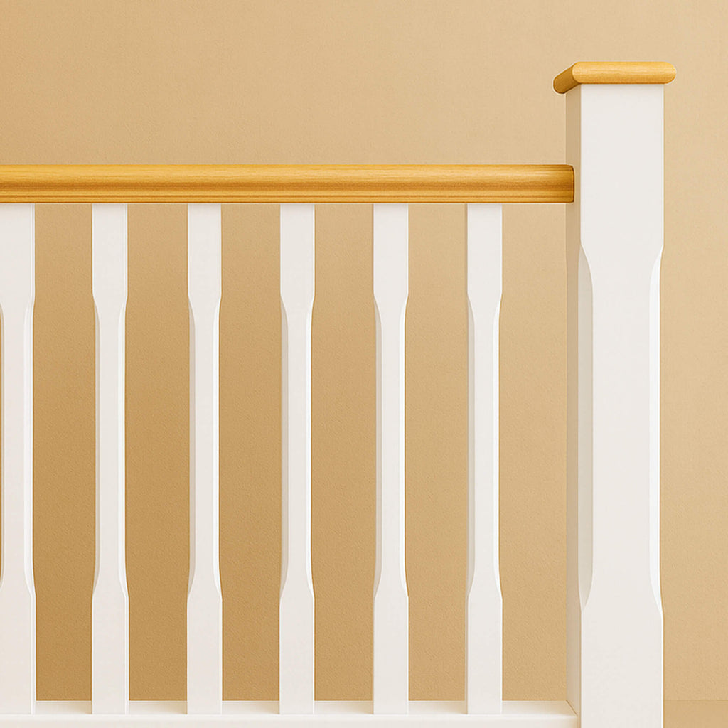 A White Primed Chamfered Newel Post with an oak pyramid newel cap, chamfered white spindles and oak handrail on a beige wall background.