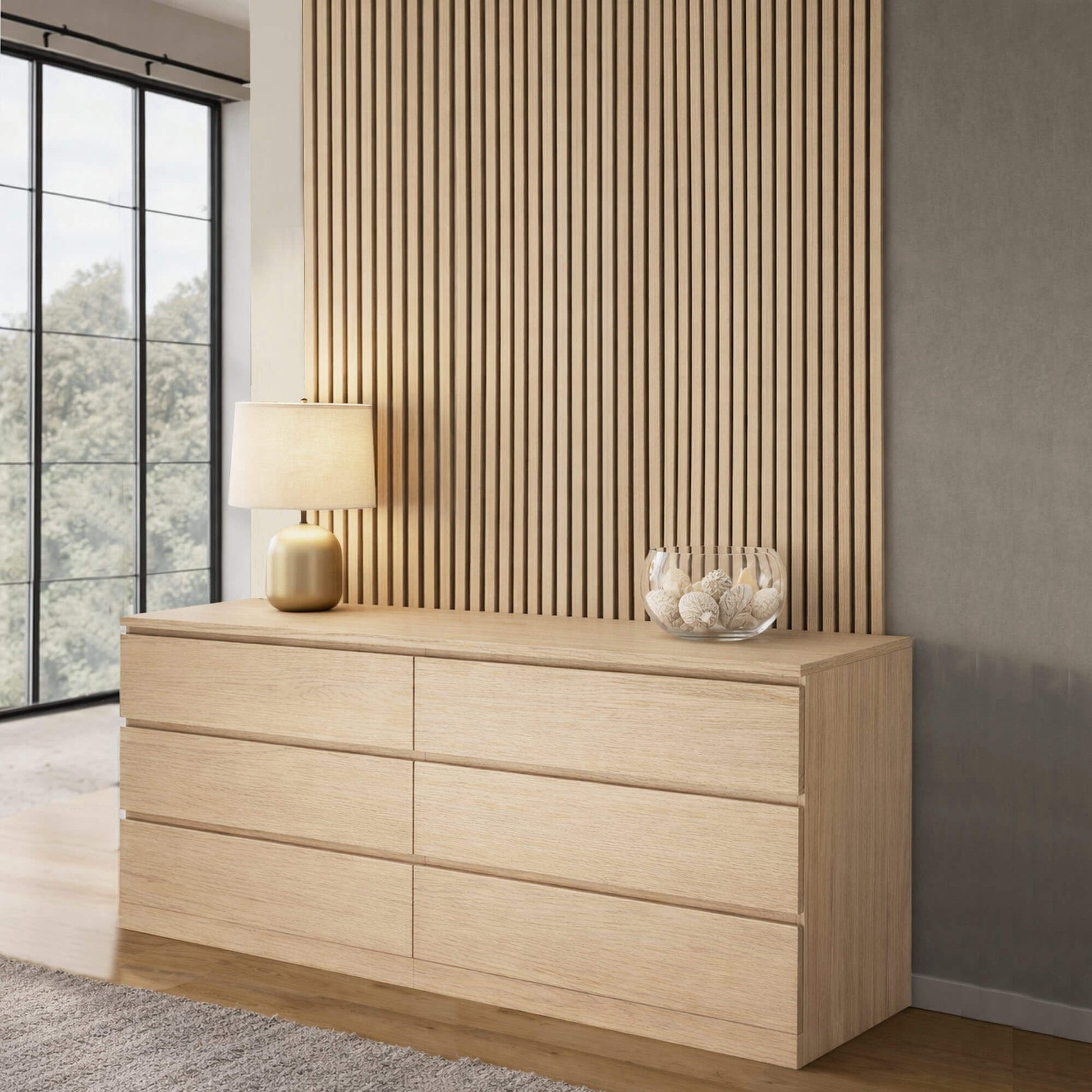 Wooden dresser with a lamp and decorative bowl against a wall with white Stained Oak Slatwall Acoustic Panel.